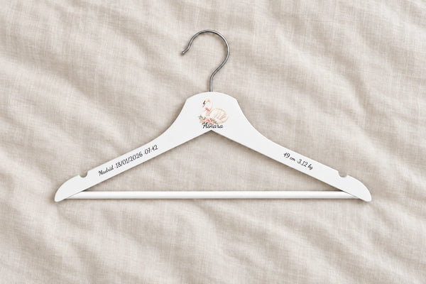 Percha bebé blanca personalizada con cisne, nombre Ainara y datos de nacimiento sobre lino claro