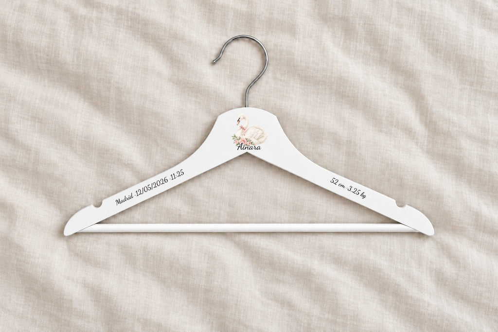 Percha bebé blanca personalizada con cisne, nombre Ainara y datos de nacimiento sobre lino claro
