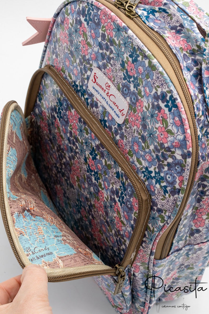 Detalle del bolsillo frontal abierto mostrando el forro interior con diseño de mapa vintage.