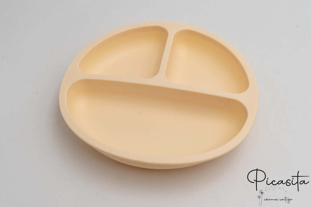 Plato infantil de silicona color crema con tres secciones para comida.
