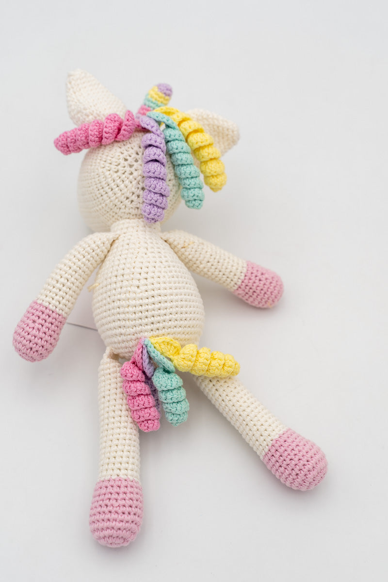Vista completa trasera de un unicornio de crochet mostrando la cola y melena multicolor.