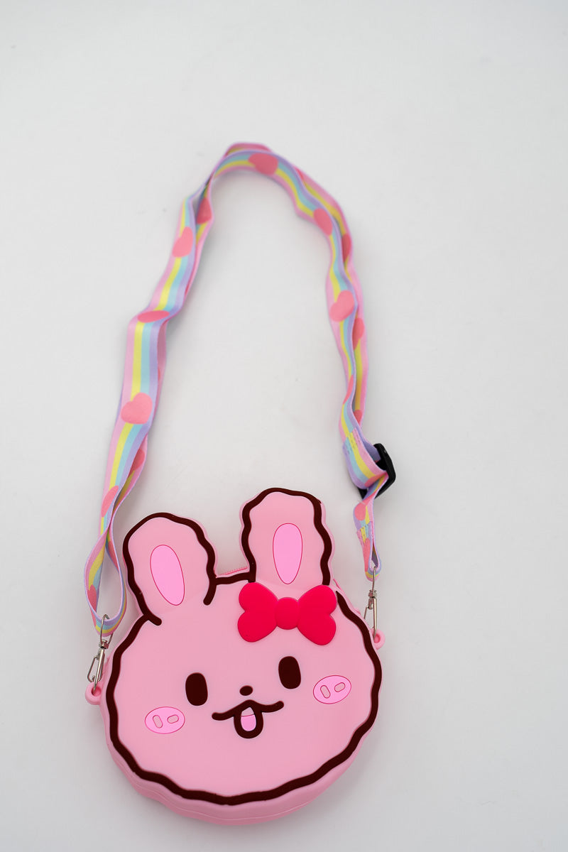 Bolso de conejo rosa con lazo rojo frontal y correa de arcoíris.
