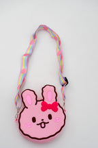 Bolso de conejo rosa con lazo rojo frontal y correa de arcoíris.