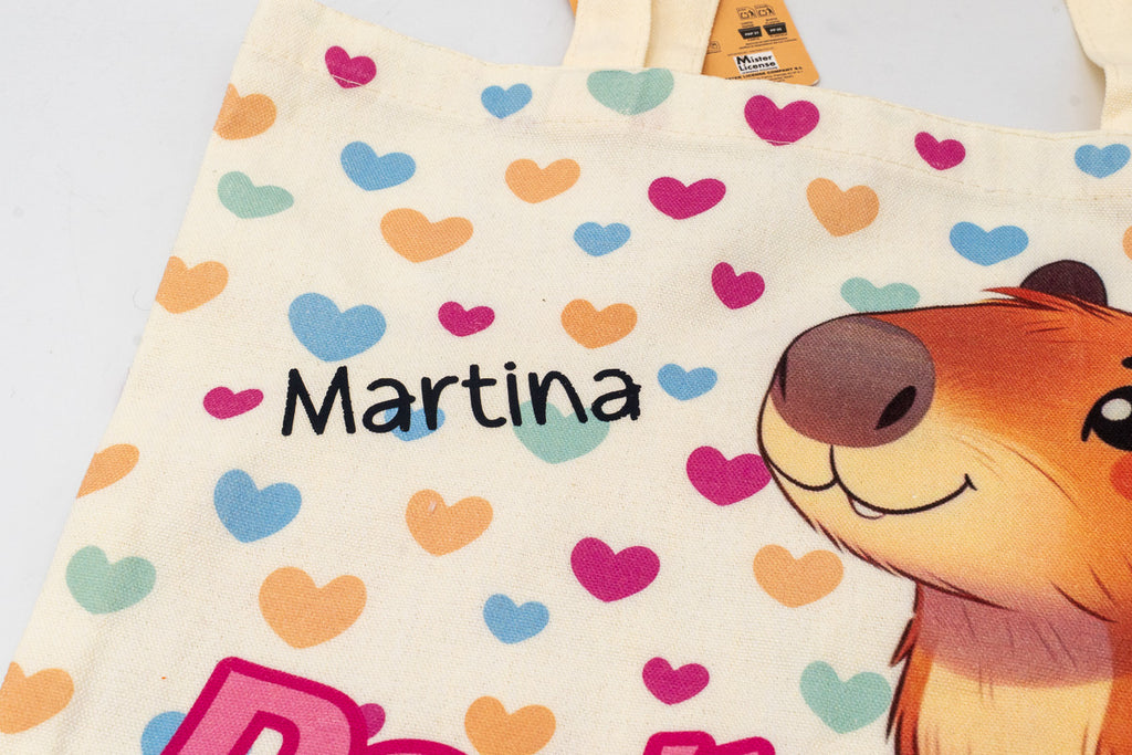 Detalle del nombre personalizado en vinilo negro sobre bolsa de algodón con ilustración de capibara.