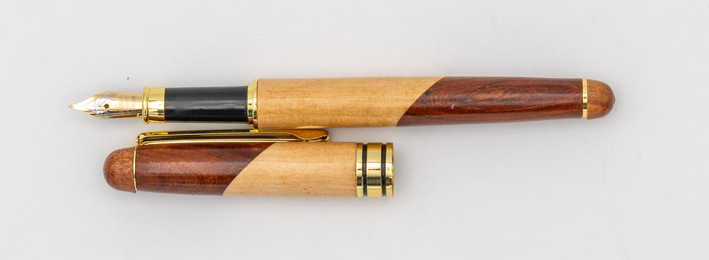 Pluma estilográfica de madera bicolor con la tapa retirada y el plumín visible.