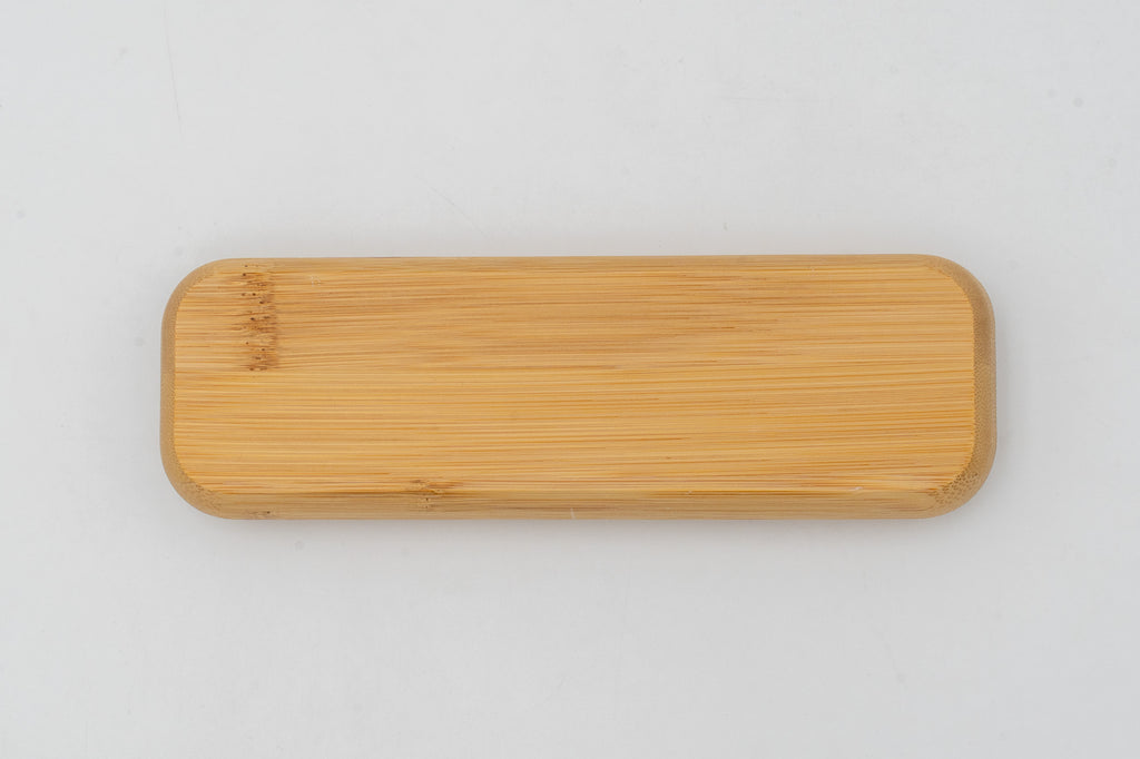 Estuche de bambú cerrado sobre fondo blanco, con la veta visible en la tapa.