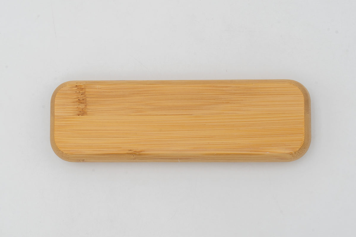 Estuche de bambú cerrado sobre fondo blanco, con la veta visible en la tapa.