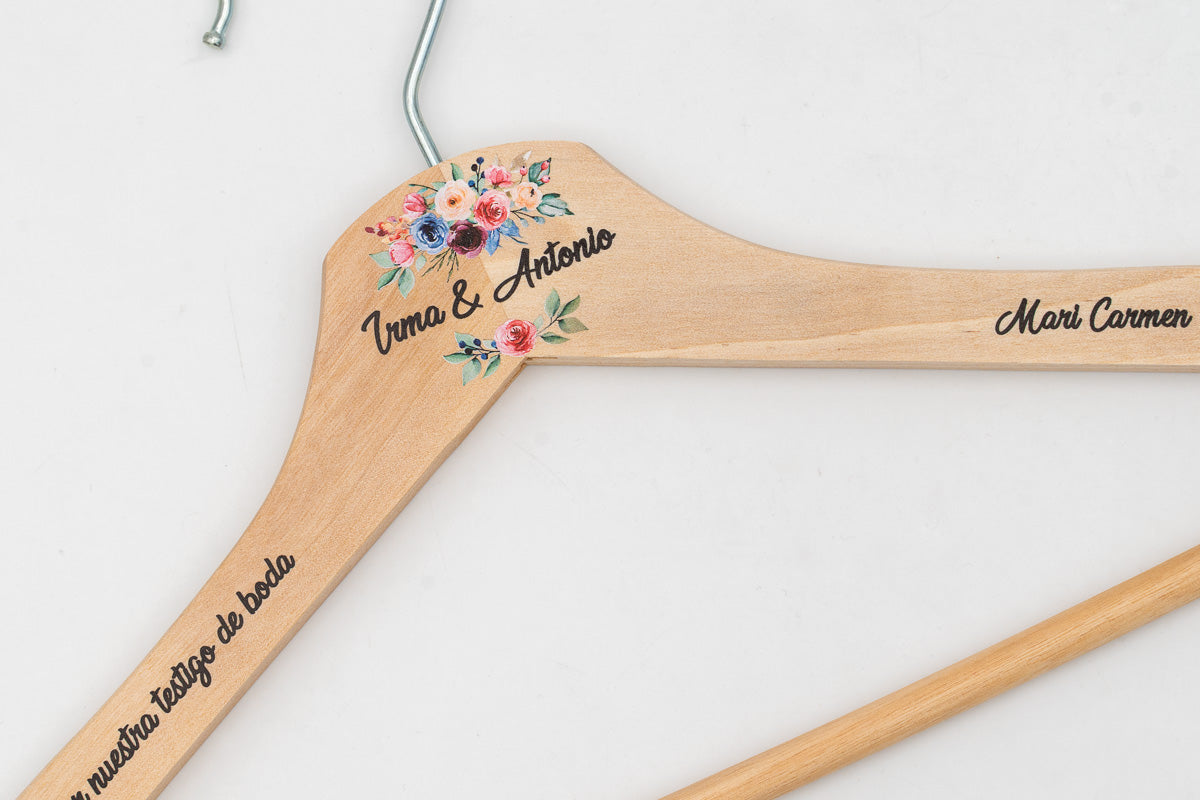 Percha de madera clara personalizada con nombres y flores, detalle del hombro