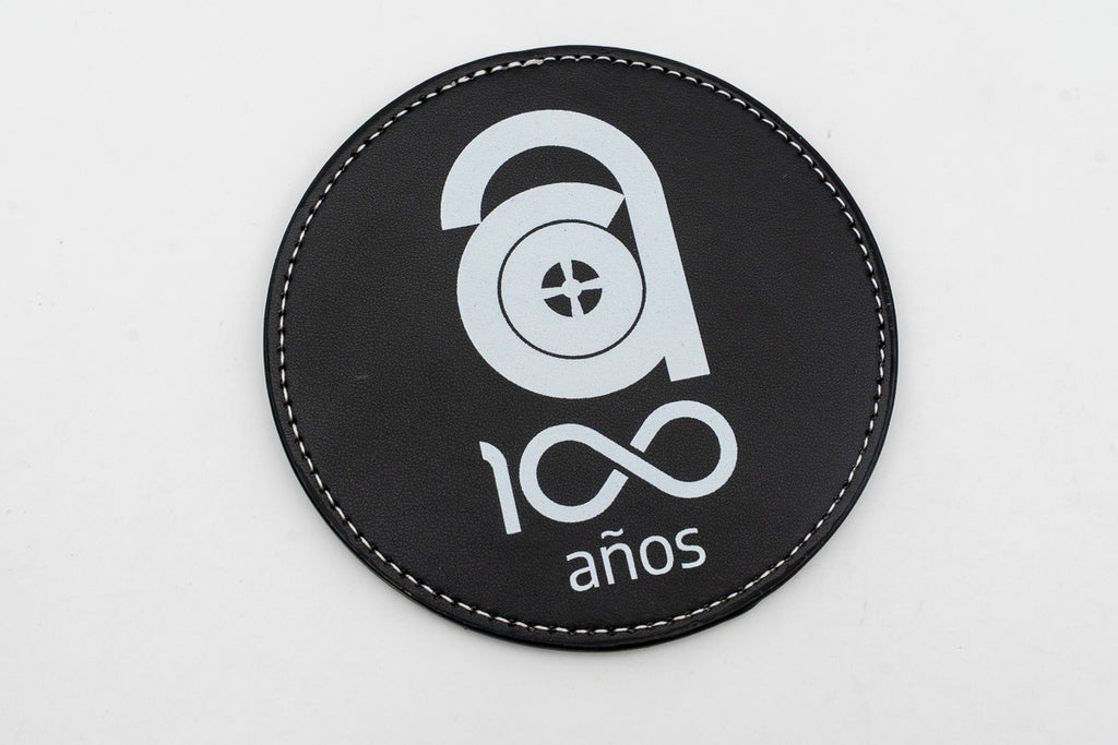 Posavasos redondo negro con logotipo conmemorativo de cien años en blanco.