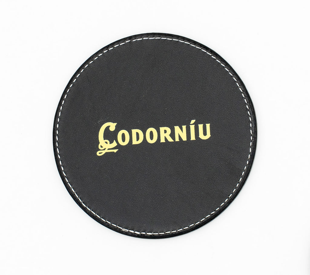 Posavasos redondo negro con logotipo Codorníu en tono dorado.