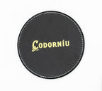 Posavasos redondo negro con logotipo Codorníu en tono dorado.