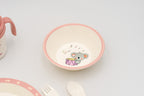 Cuenco infantil rosa con ilustración central de un koala durmiendo sobre un tambor.