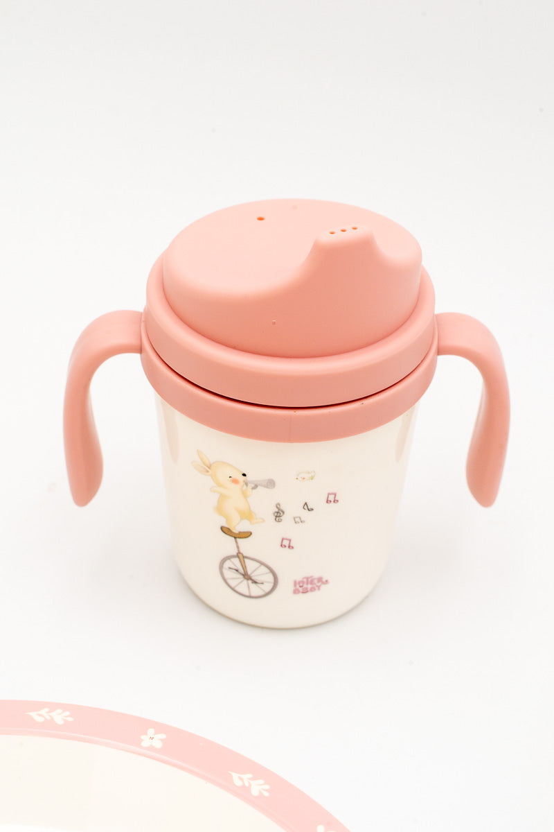 Vaso de aprendizaje rosa con dos asas laterales y tapa con boquilla antigoteo.