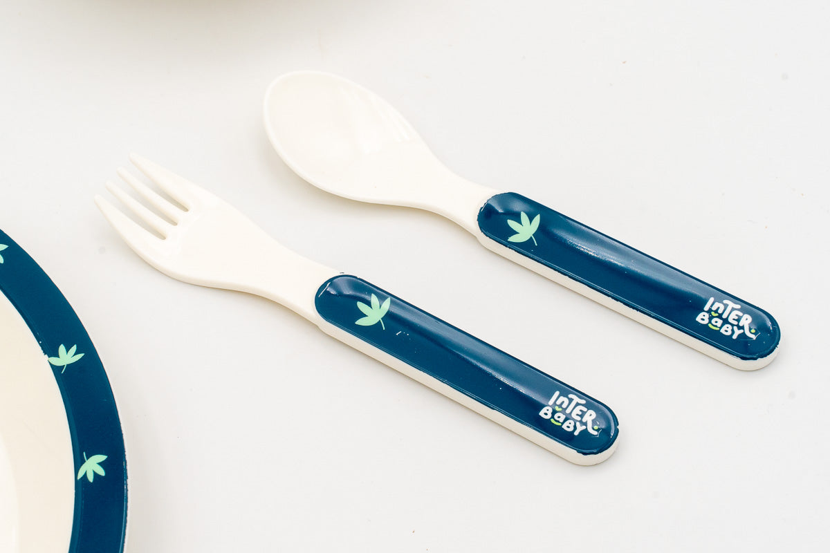 Tenedor y cuchara infantiles azules con mango ergonómico y detalle de hoja verde.
