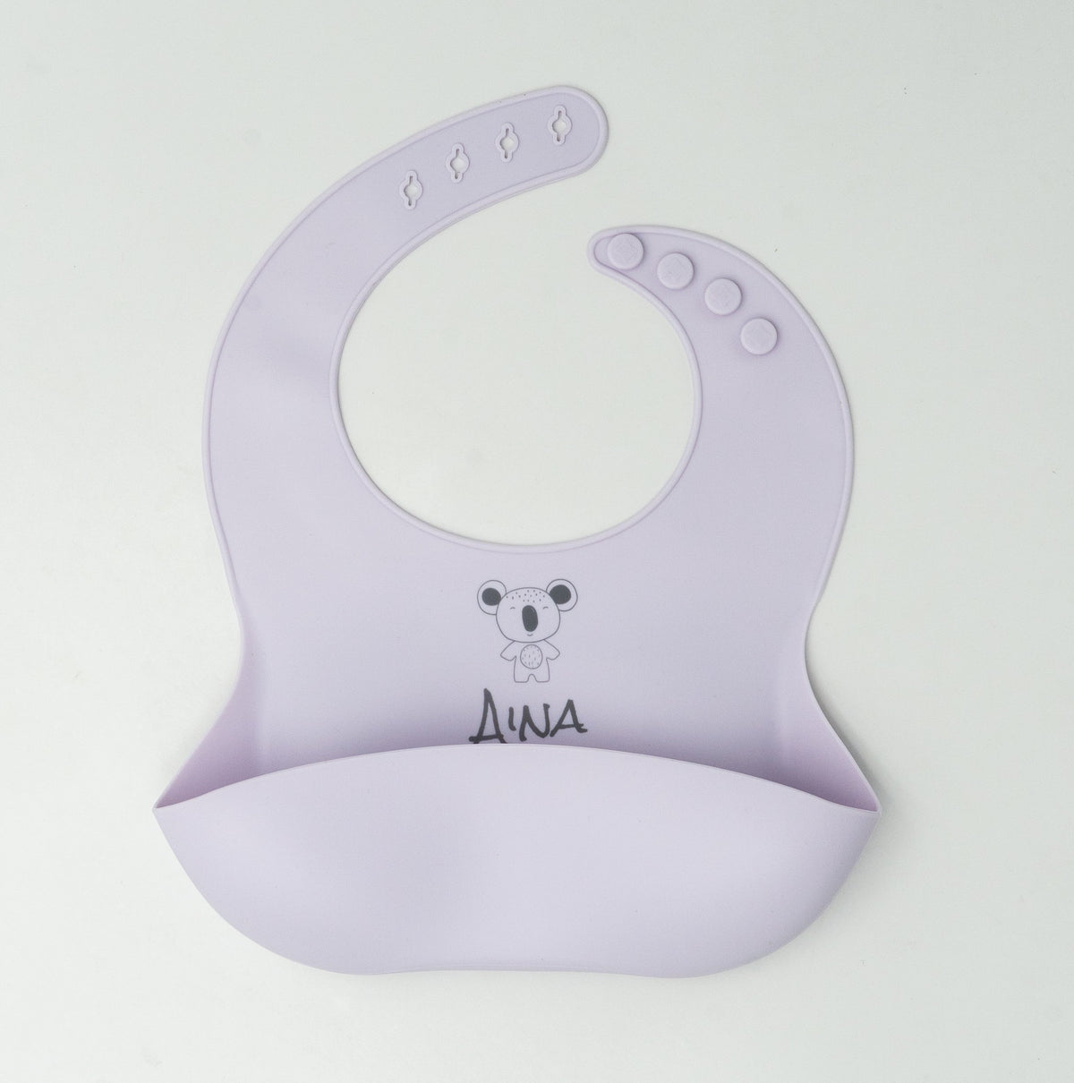 Babeiro de silicona de cor lila claro co nome Aina e un koala gravados