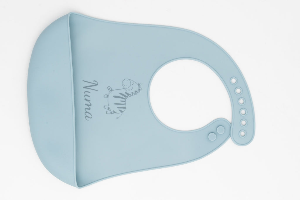 Pitet de silicona blau clar amb nom i dibuix de girafa, col·locat de costat.