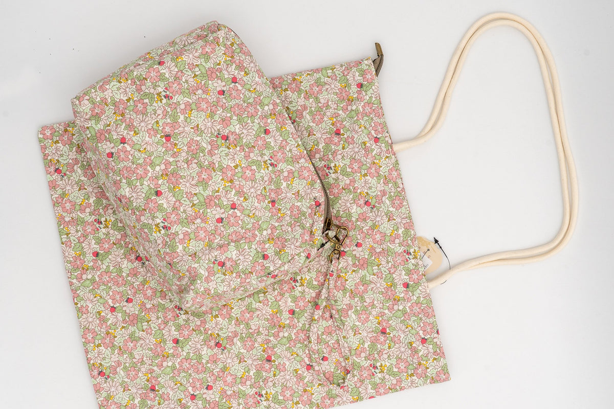 Neceser e bolsa de algodón con estampado floral en tons rosa e verde sobre fondo branco.