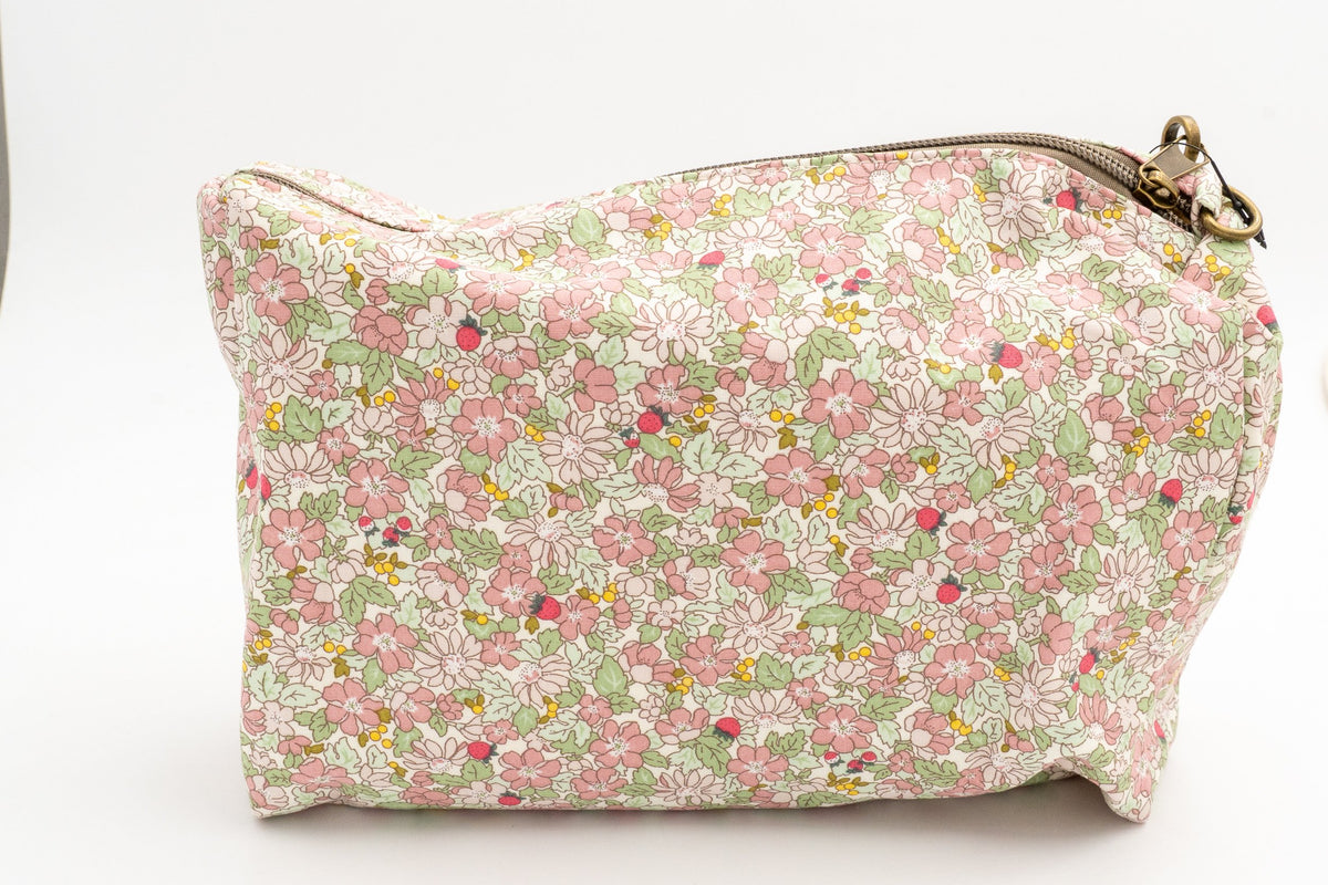 Detalle de neceser floral rosa con cierre de cremallera metálica y tirador de tela.