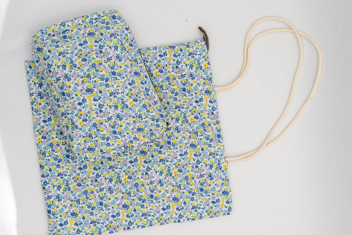 Conxunto de neceser e bolsa con deseño de flores pequenas azuis e amarelas.