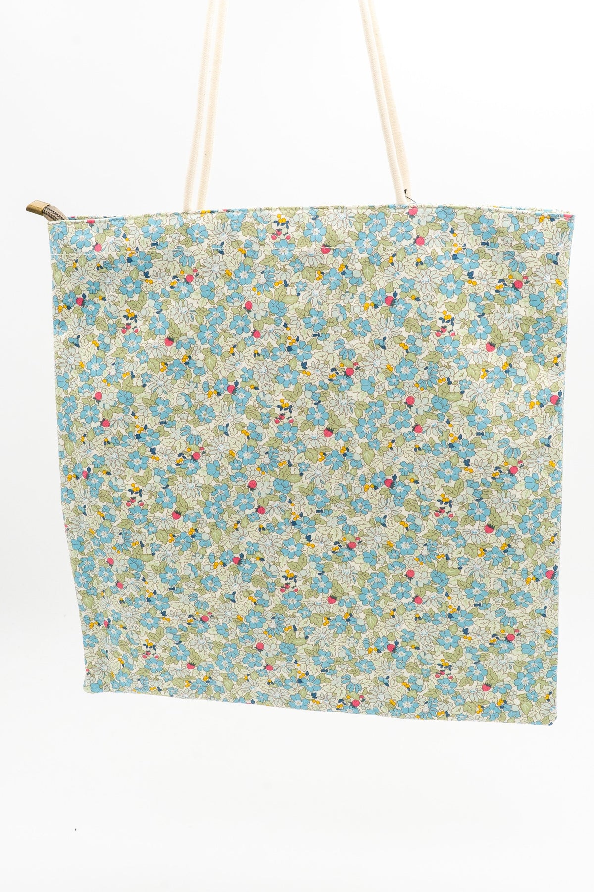 Bolsa tote con estampado de flores verdes y blancas colgada verticalmente mostrando su capacidad.