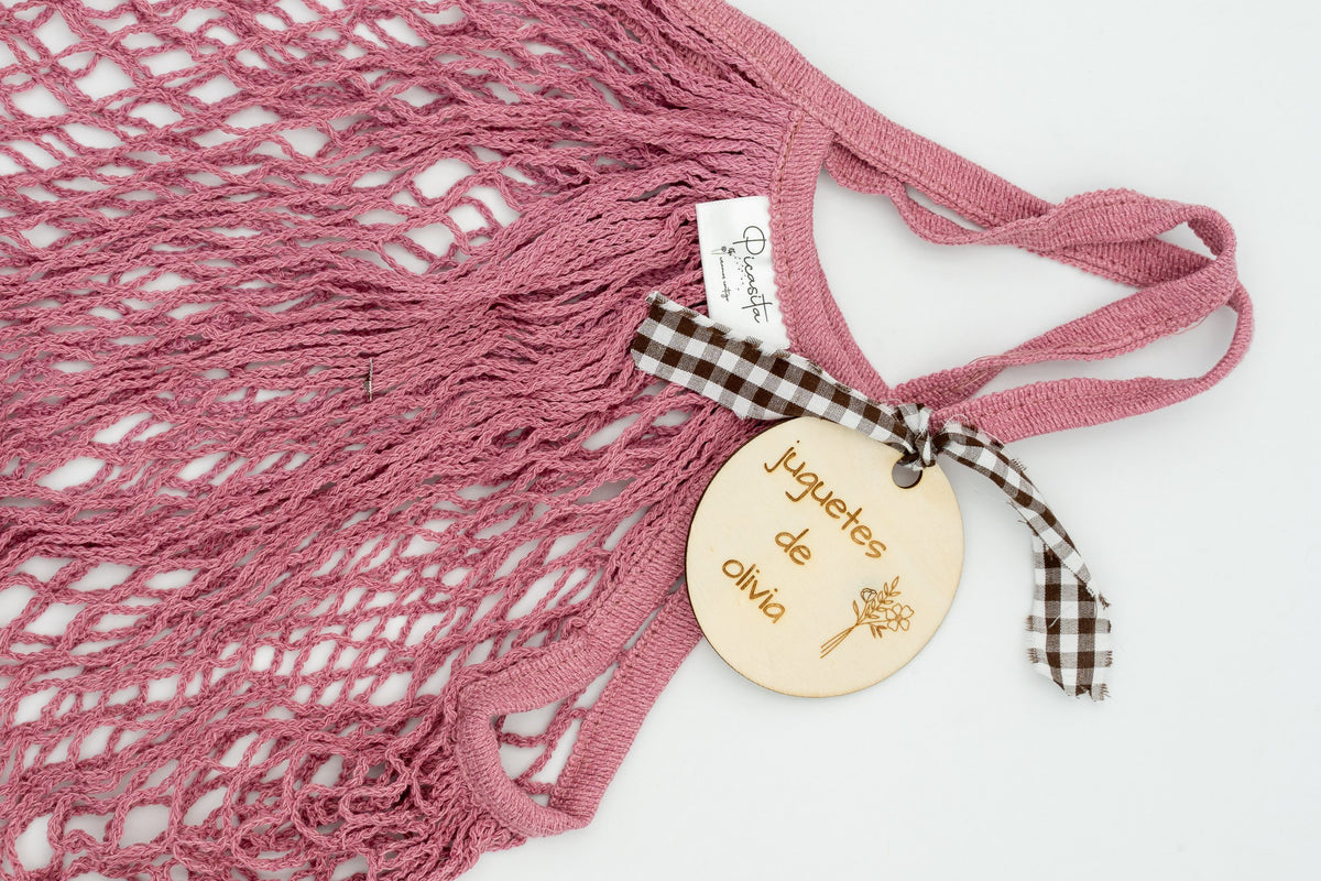 Primeiro plano dunha placa de madeira gravada a láser nunha bolsa rosa escuro.