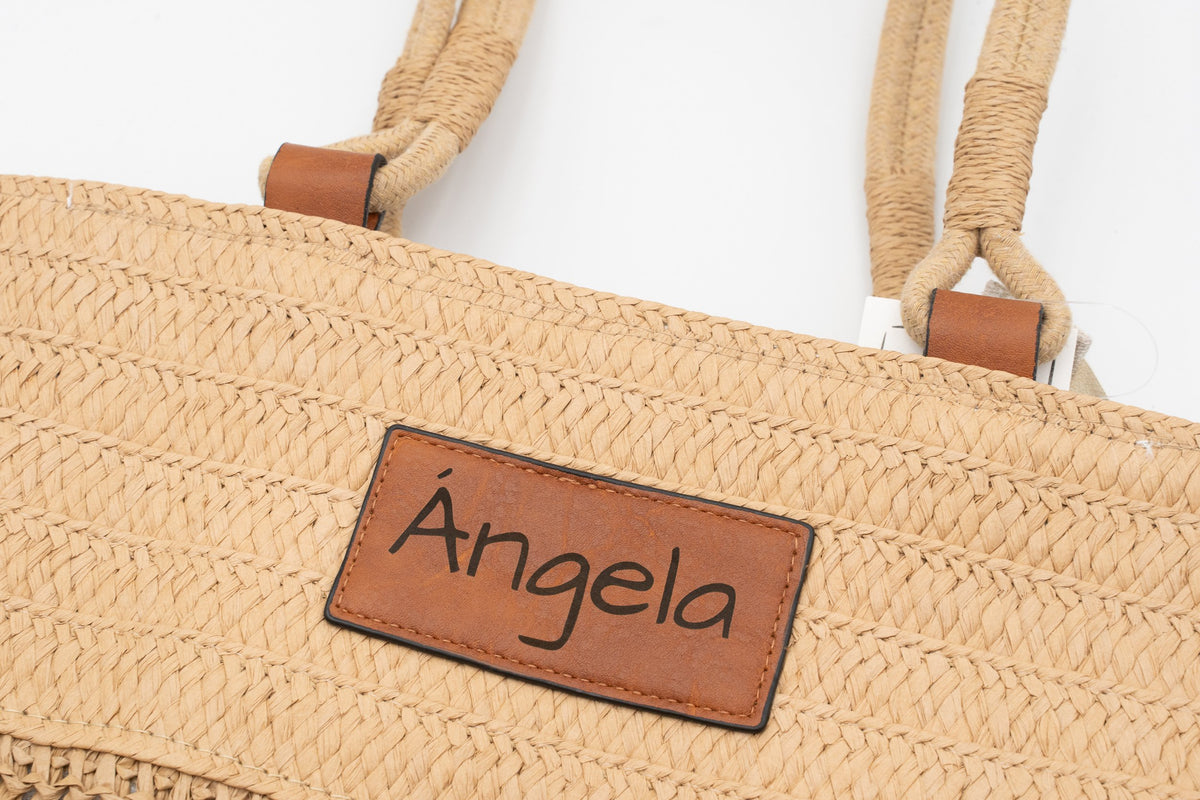 Parche de cuero sintético de un bolso de rafia grabado con el nombre Ángela