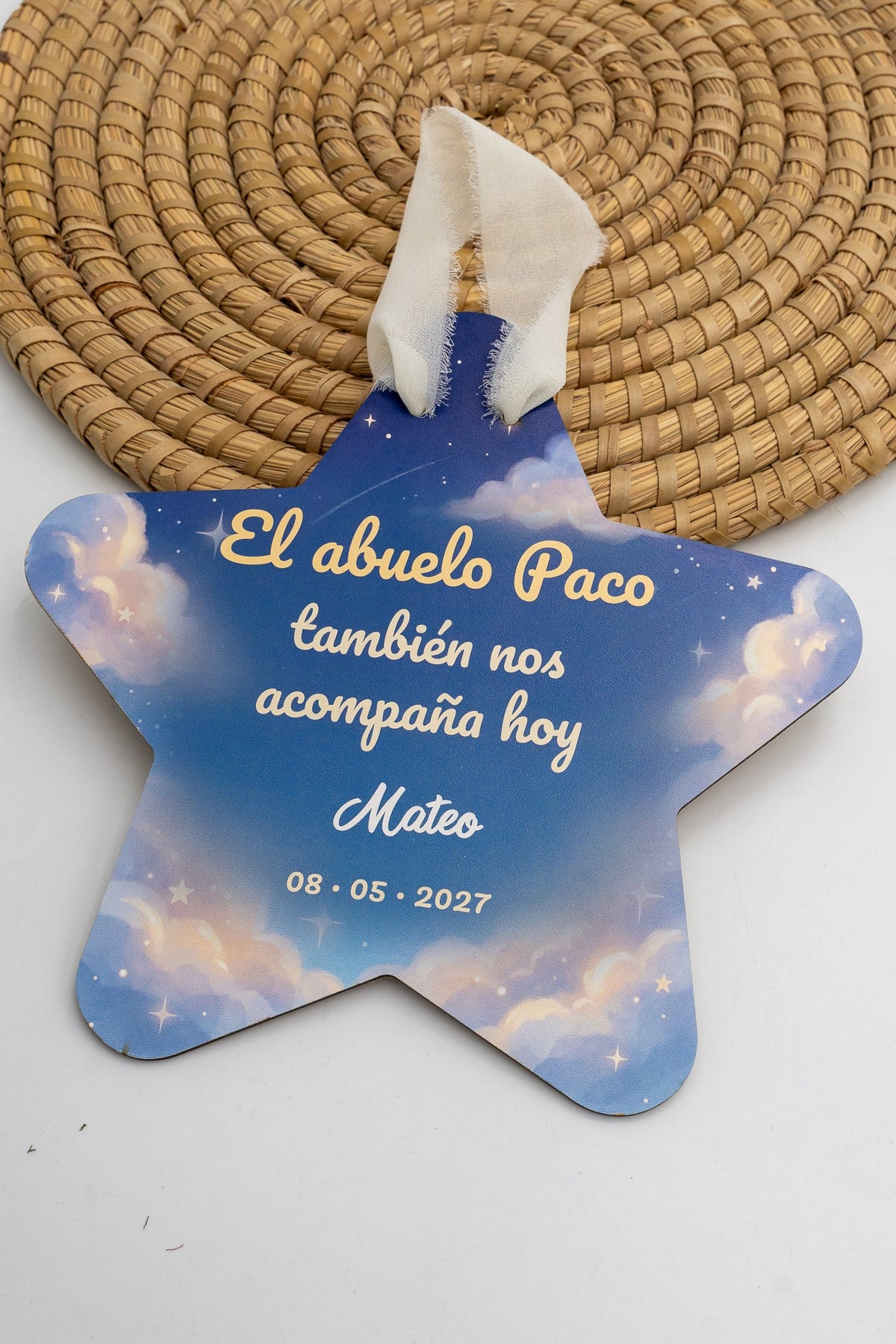 Estrela de comuñón con fondo de ceo azul con nubes e estrelas, a frase «El abuelo Paco también nos acompaña hoy», o nome de exemplo Mateo e a data, con cinta crema.
