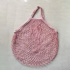 Bolsa de malla en tono rosa clarito mostrando su estructura de red flexible.