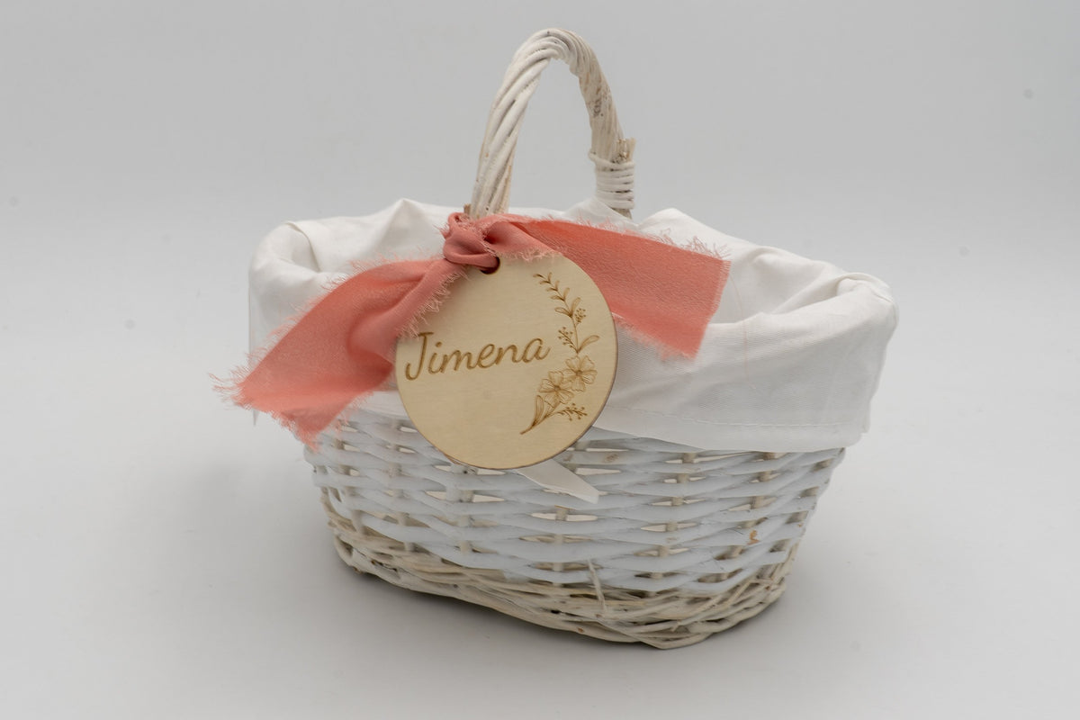 Cistell blanc amb folre de tela, llaç salmó i cercle amb el nom Jimena gravat