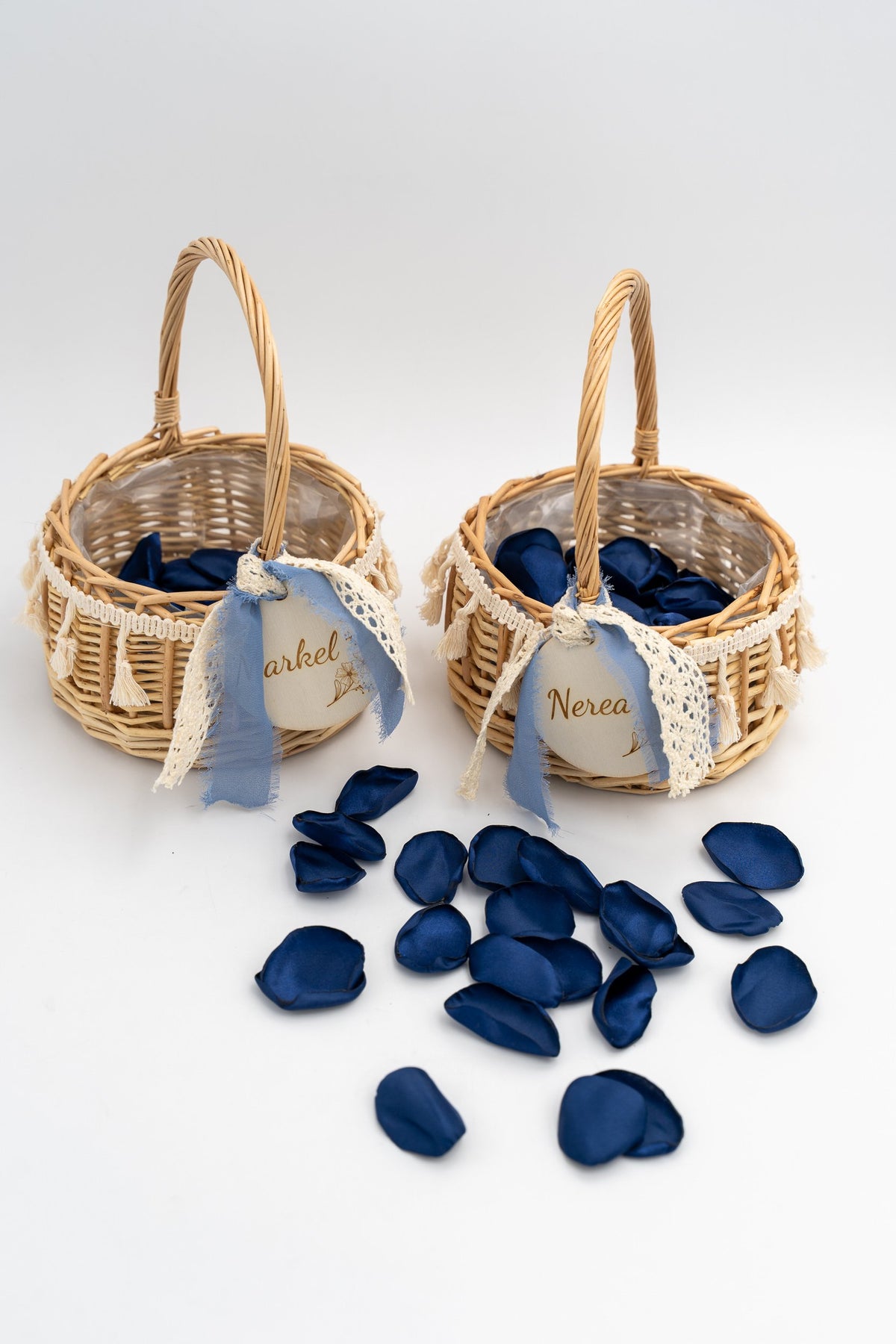 Dos cistellets de rotang per a nens d'arres envoltats de pètals blau marí
