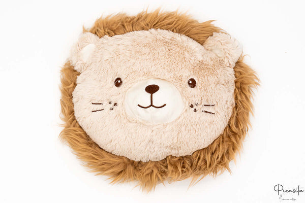 Cojín de león con melena de pelo largo marrón y cara de peluche beige con patrón calado.