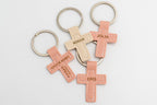 Dos llaveros de cruz en tonos rosa y beige con nombres personalizados