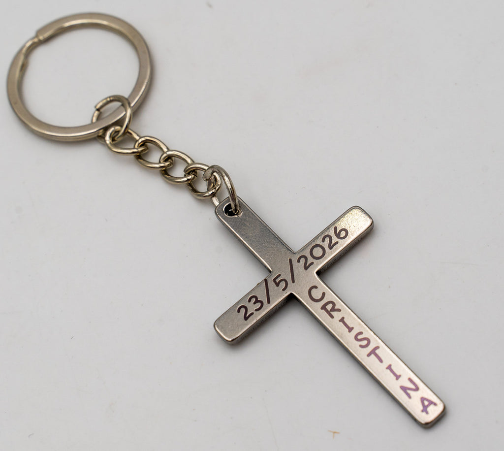 Llavero metálico con cruz fina y texto personalizado sobre fondo claro