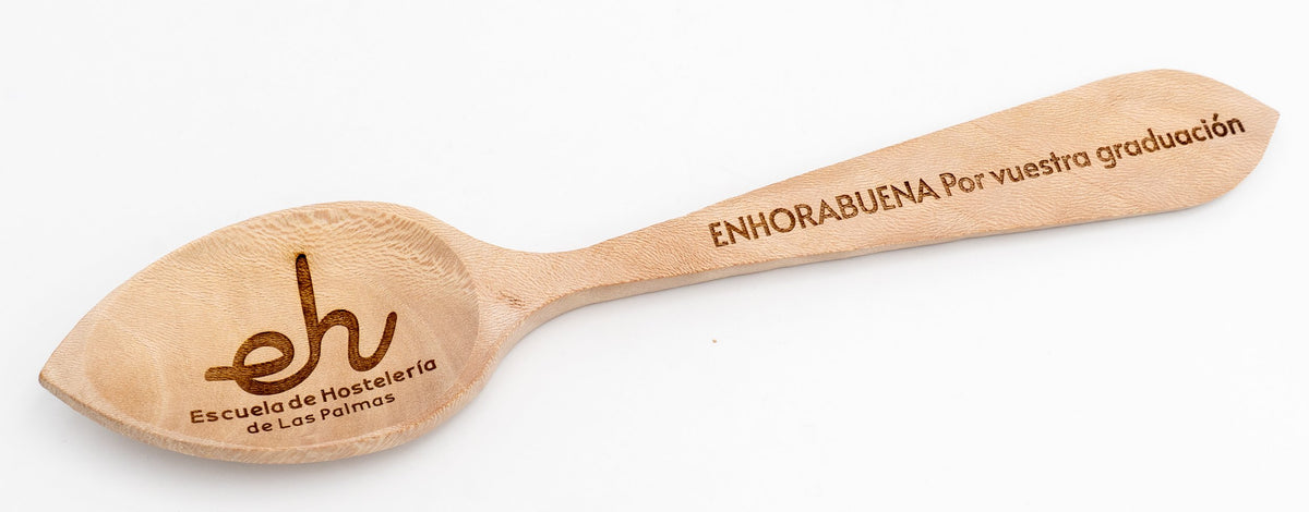 Cuchara de madera con dedicatoria de graduación y logotipo institucional en tonos marrones oscuros.