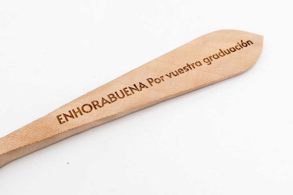 Detalle macro del mensaje de enhorabuena grabado sobre el veteado natural de la madera.