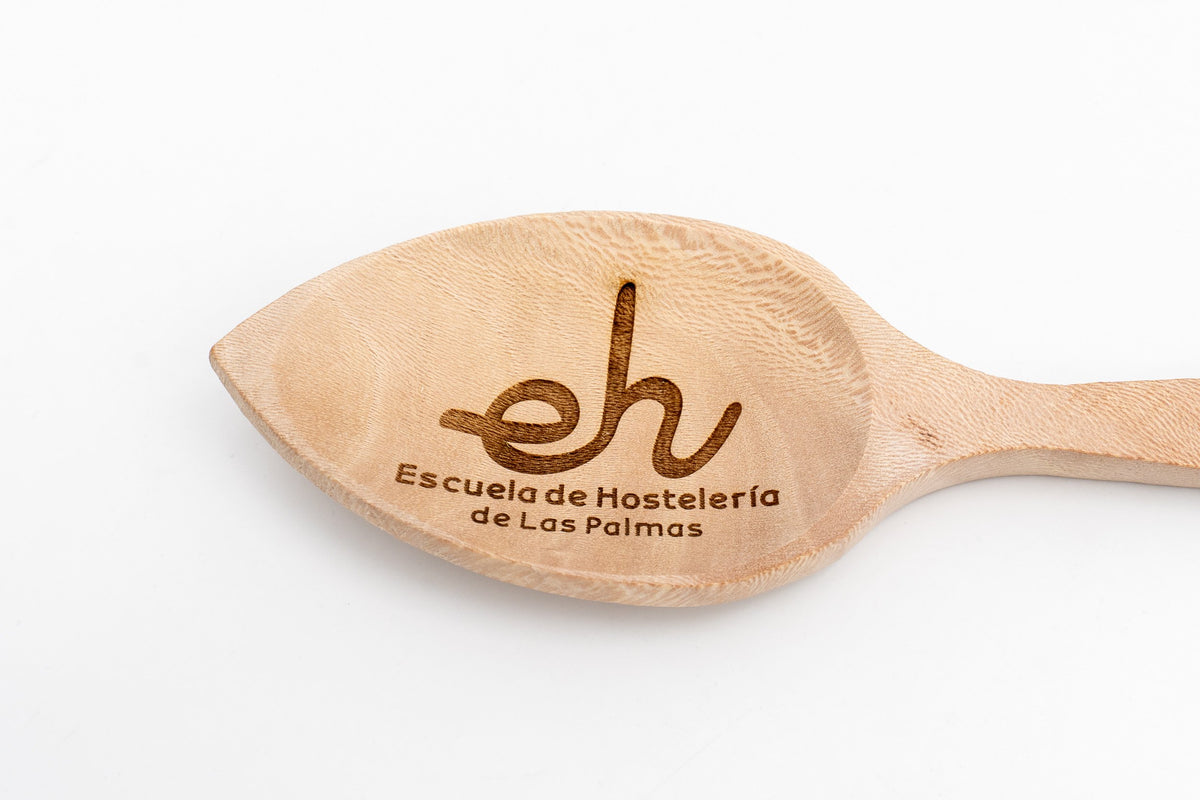 Detalle del grabado láser con logotipo de escuela de hostelería en la pala de una cuchara.