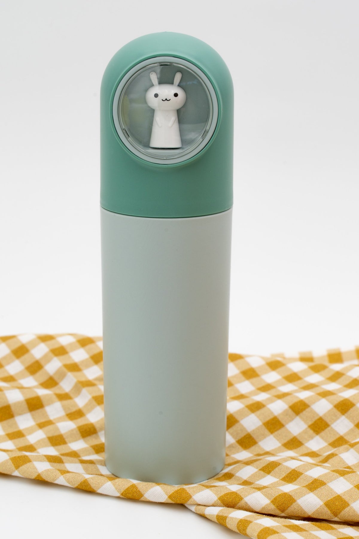 Estoig de polipropilè de color verd amb cúpula transparent i figura de conill blanc.