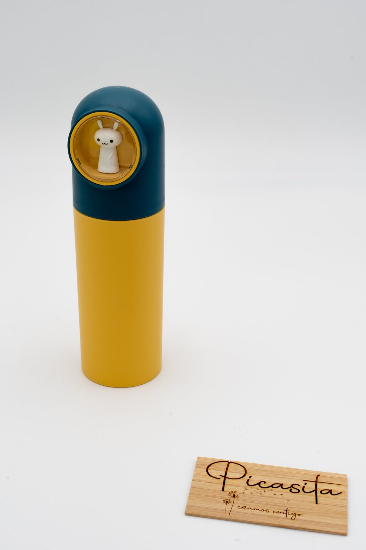 Estuche azul y amarillo junto a placa de madera con logotipo de Picasita.