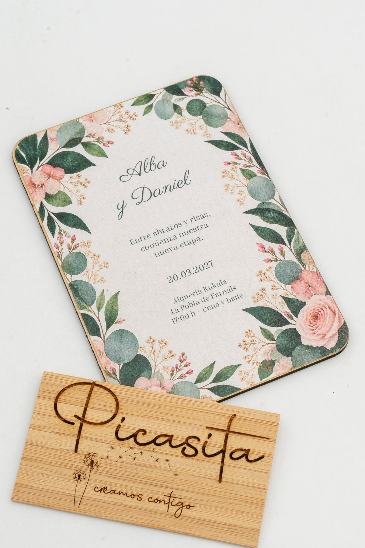 Invitación de voda de madeira con follas de eucalipto e rosas nas esquinas