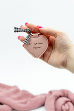 Man sostendo un chaveiro de corazón con texto e lazo vichy.