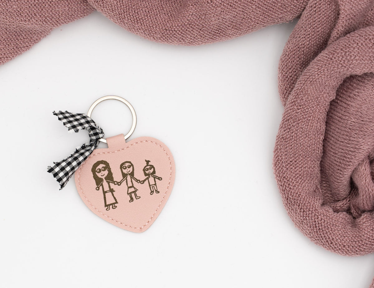 Chaveiro de corazón rosa con debuxo de tres persoas e lazo vichy negro.