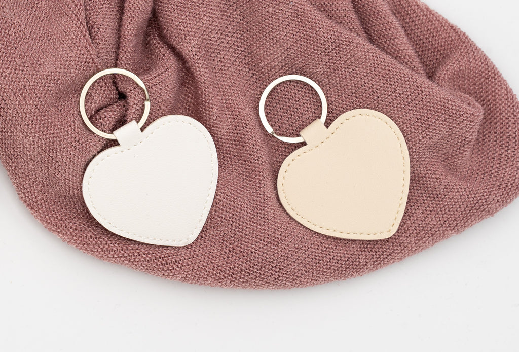 Chaveiros de corazón branco e beixe sen personalizar sobre tea rosa.