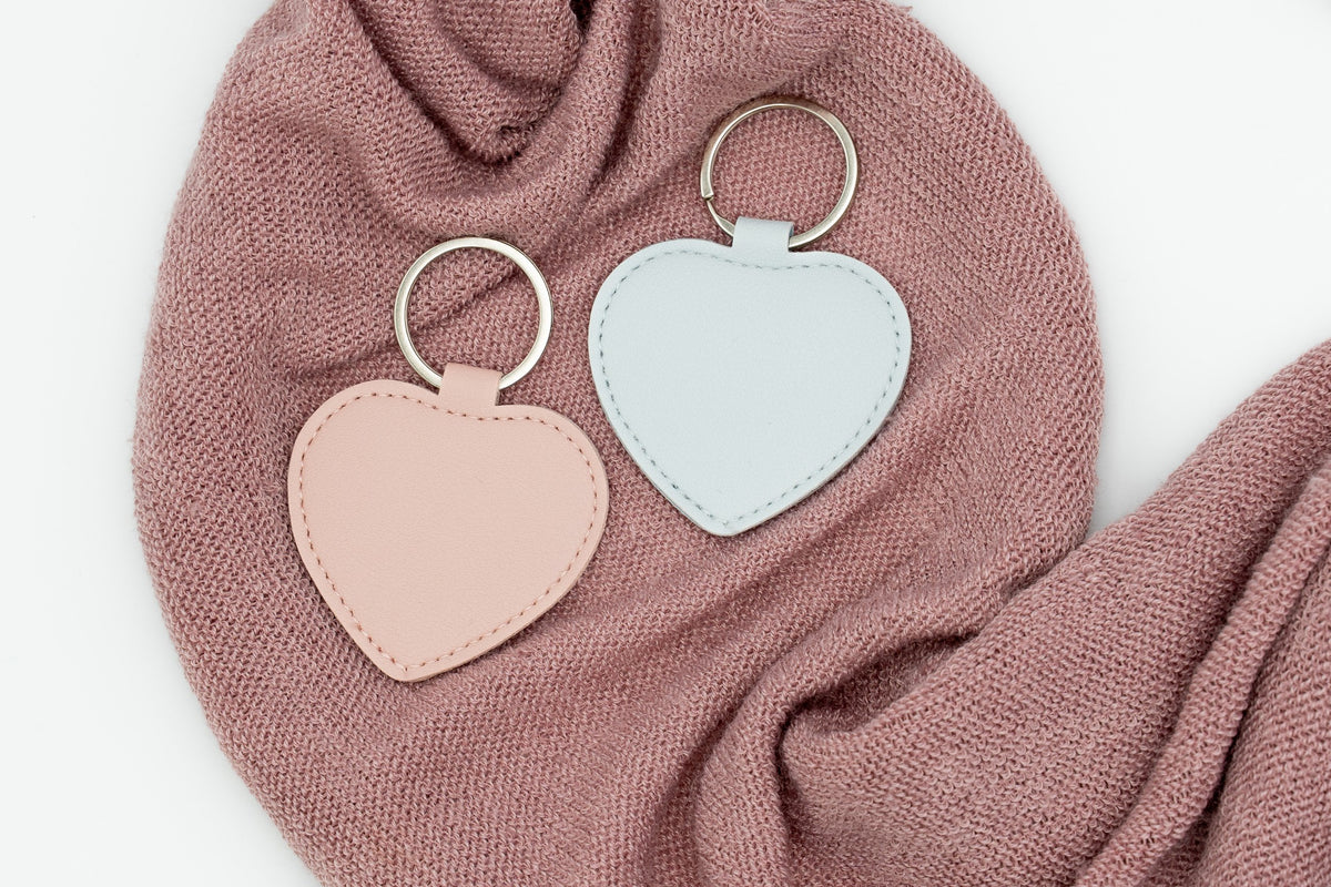 Chaveiros de corazón rosa e azul claro sen personalizar sobre tea rosa.