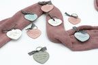 Chaveiros de corazón de varias cores con dedicatorias sobre unha tea rosa.