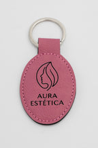 Clauer ovalat rosa amb símbol d'estètica i text fosc.