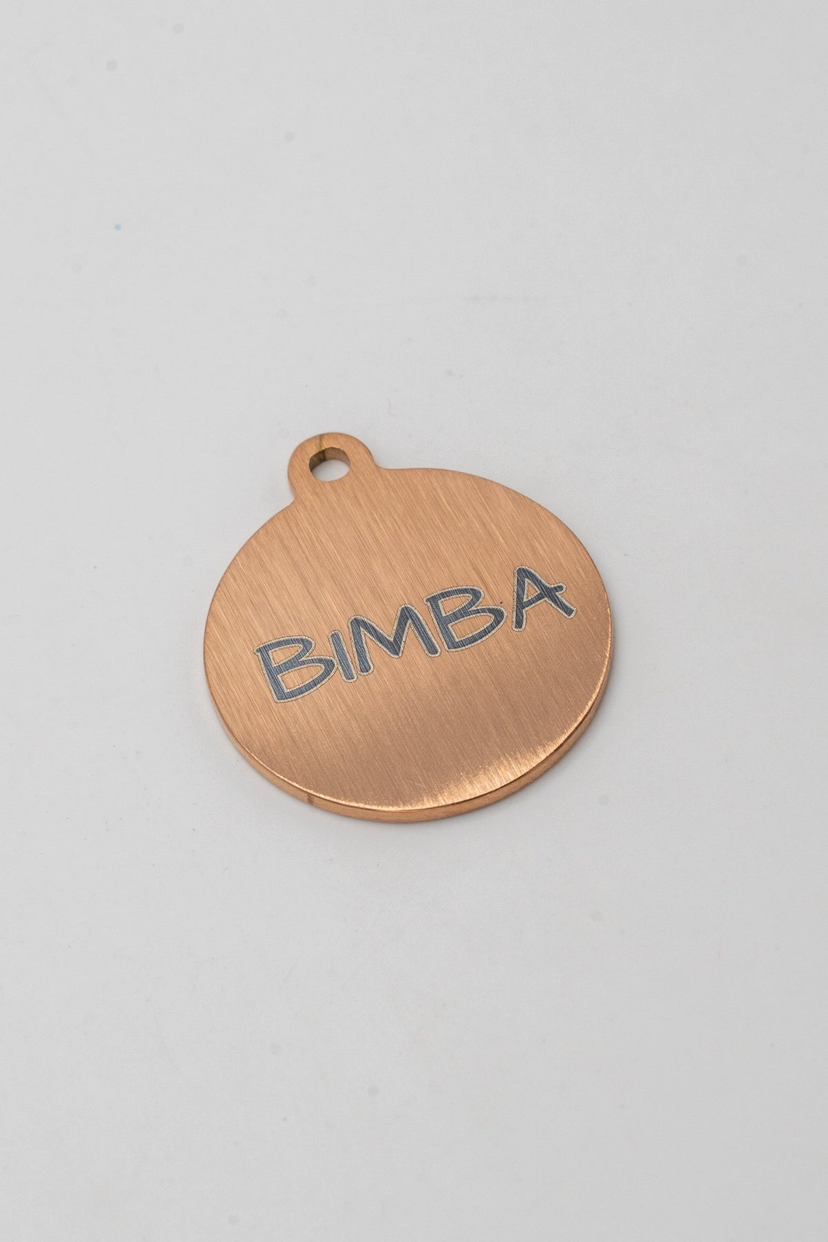 Cara posterior de medalla rosada para perro con el nombre BIMBA grabado a láser