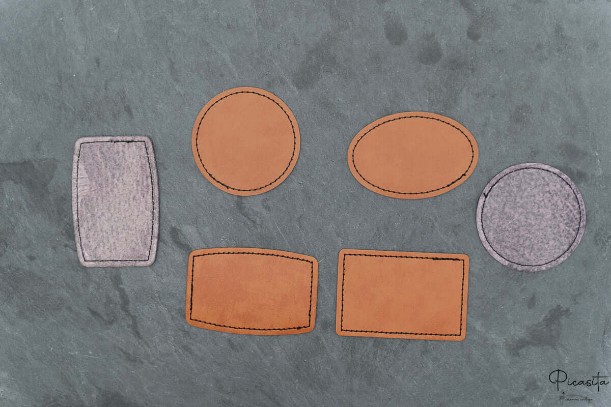 Conjunto de parches personalizados en diferentes formas geométricas sobre una superficie de piedra gris.