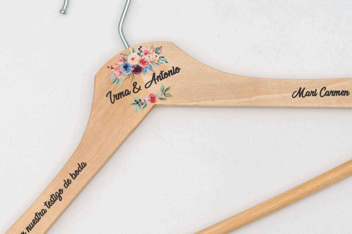Percha de madeira clara personalizada con nomes e flores, detalle do ombreiro.