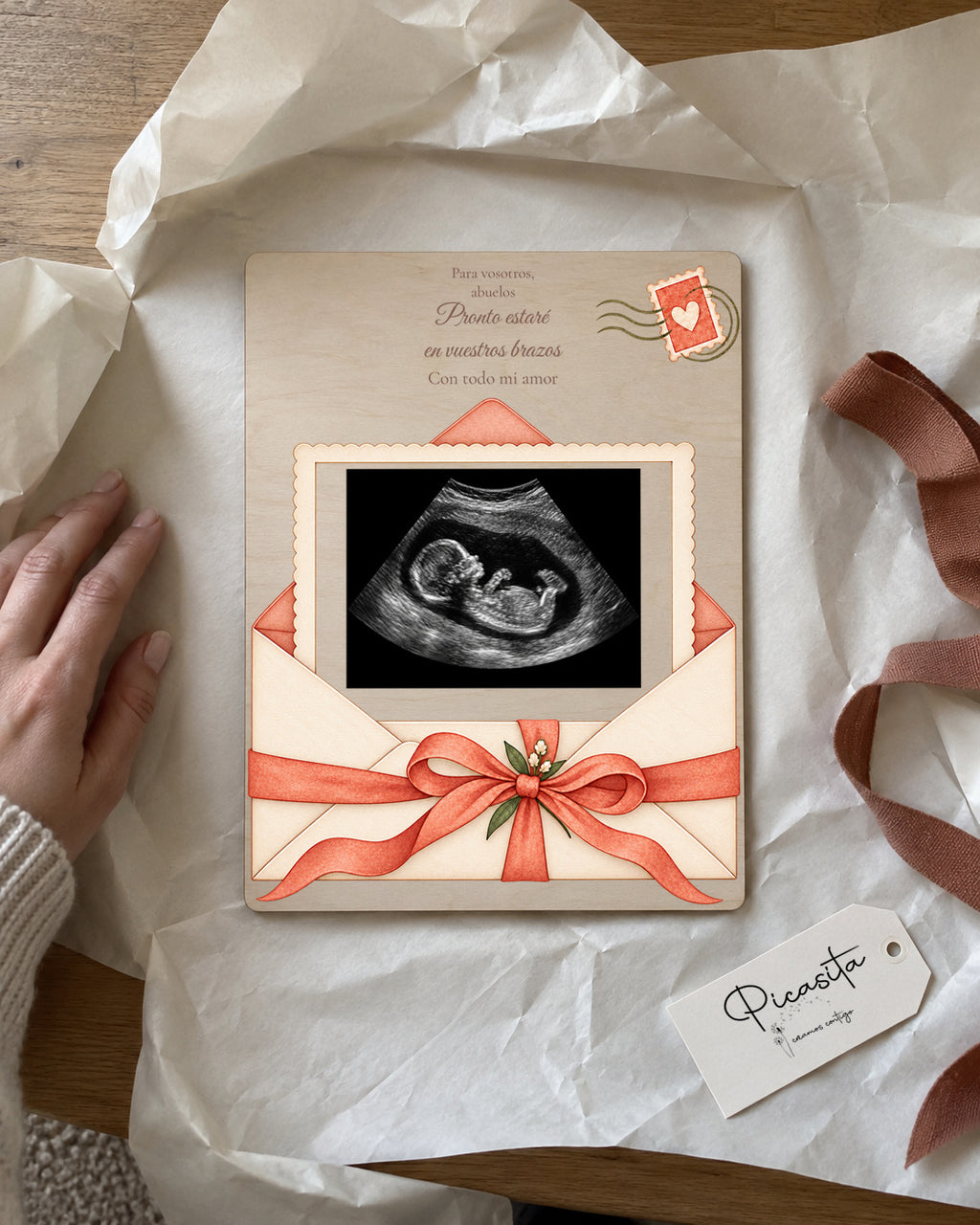 Vista previa simulada: Carta del bebé en Contrachapado, 15 × 20 cm, con ecografía sintética ilustrativa. Escena de regalo.