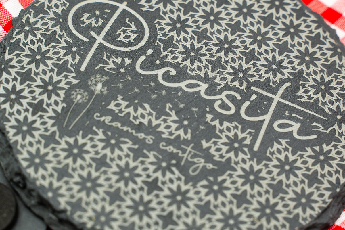 Detalle de posavasos redondo de lousa con logotipo floral gravado.